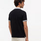 A man wearing a black short-sleeve polo shirt with white striped trim on the collar and sleeve cuffs, shown from a rear three-quarter view against a plain white background.