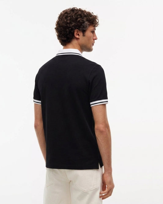 A man wearing a black short-sleeve polo shirt with white striped trim on the collar and sleeve cuffs, shown from a rear three-quarter view against a plain white background.