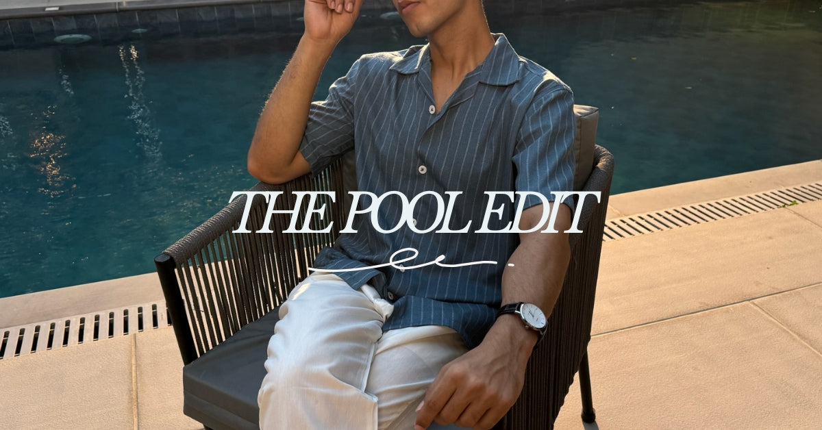 A man sitting in a dark woven outdoor chair by a swimming pool, wearing a blue-and-white vertically striped short-sleeve button-up shirt and white pants. Large overlaid text reads 'THE POOL EDIT'.